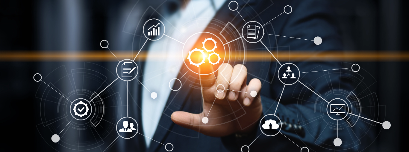 Close-up of a business professional reaching towards a glowing graphic of interconnected gears surrounded by icons for data analysis, documents, human resources, and cloud storage, against a dark background, illustrating themes of technology, collaboration, and data management.